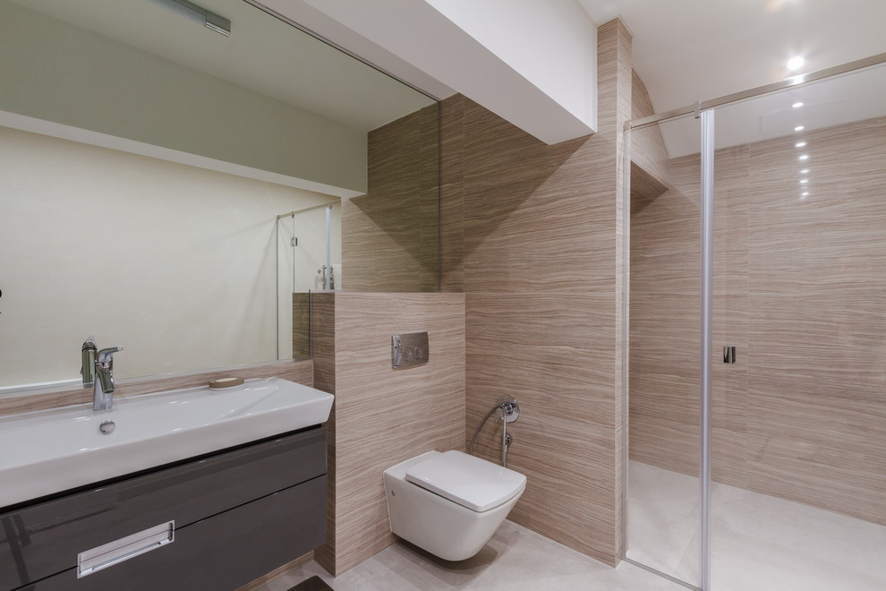 На фото: ванная комната среднего размера в современном стиле с серыми фасадами, инсталляцией, бежевой плиткой, керамогранитной плиткой, бежевыми стенами, полом из керамогранита, подвесной раковиной и серым полом с