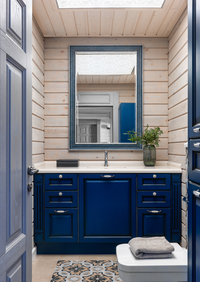 Modelo de aseo tradicional renovado con armarios con paneles con relieve, puertas de armario azules, lavabo bajoencimera, suelo beige y encimeras beige