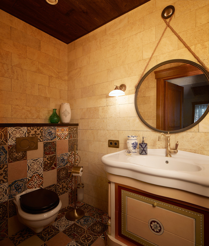 Kleine Mediterrane Gästetoilette mit Wandtoilette, beigen Fliesen, farbigen Fliesen, beiger Wandfarbe, Mosaik-Bodenfliesen, buntem Boden, Travertinfliesen und integriertem Waschbecken in Jekaterinburg