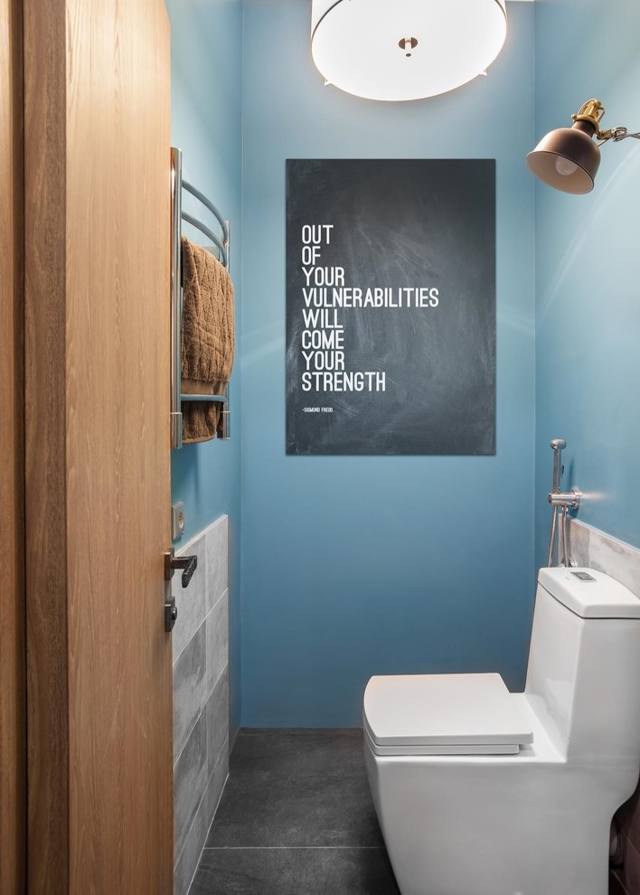Cette photo montre un WC et toilettes tendance avec WC à poser, un mur bleu et un sol gris.