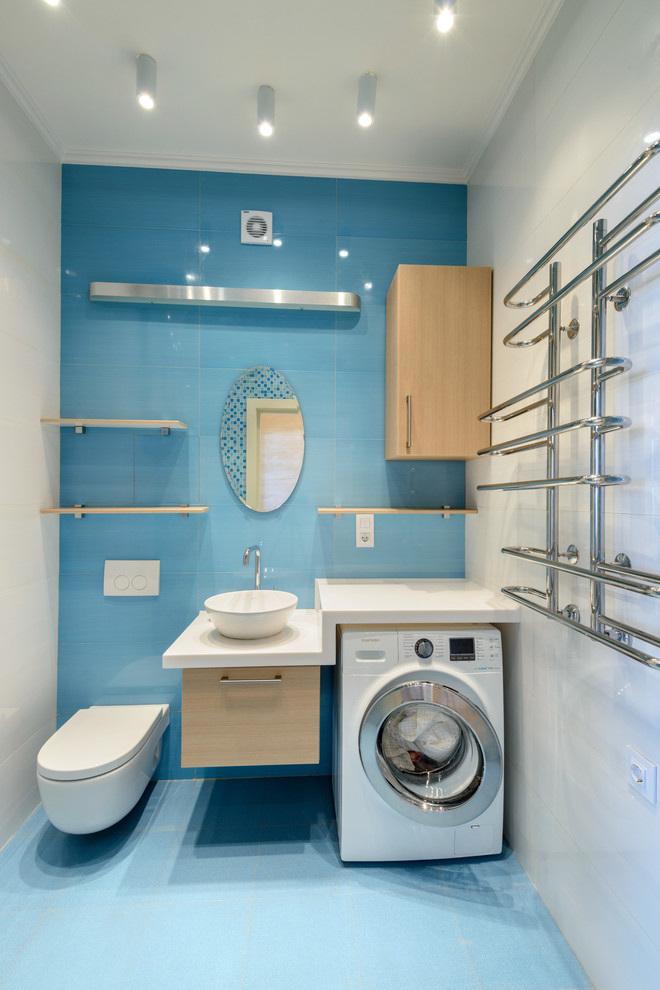 Réalisation d'un WC suspendu design en bois clair de taille moyenne avec un placard à porte plane, un carrelage bleu, un carrelage blanc, un sol en carrelage de céramique, un plan de toilette en surface solide et une vasque.