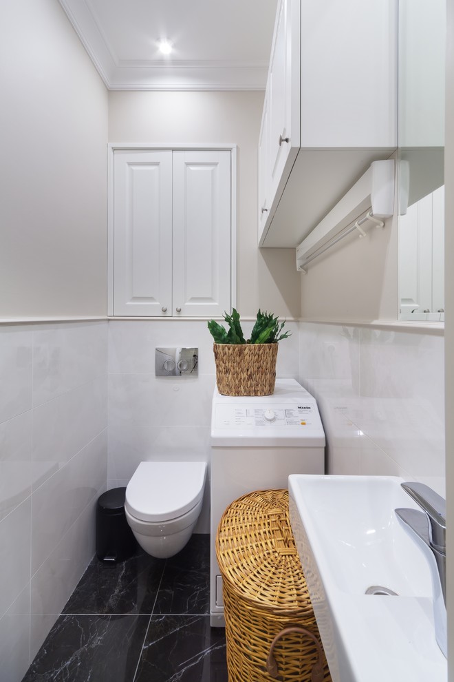 エカテリンブルクにあるコンテンポラリースタイルのおしゃれなトイレ・洗面所 (壁掛け式トイレ、白いタイル、ベージュの壁、壁付け型シンク、黒い床) の写真