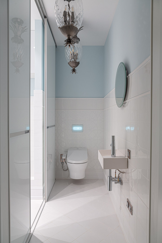 Réalisation d'un grand WC et toilettes design avec des portes de placard blanches et un carrelage blanc.