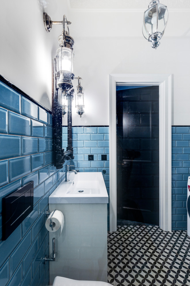 Idéer för små industriella vitt toaletter, med luckor med profilerade fronter, vita skåp, en vägghängd toalettstol, blå kakel, keramikplattor, blå väggar, klinkergolv i keramik, ett fristående handfat, bänkskiva i akrylsten och svart golv