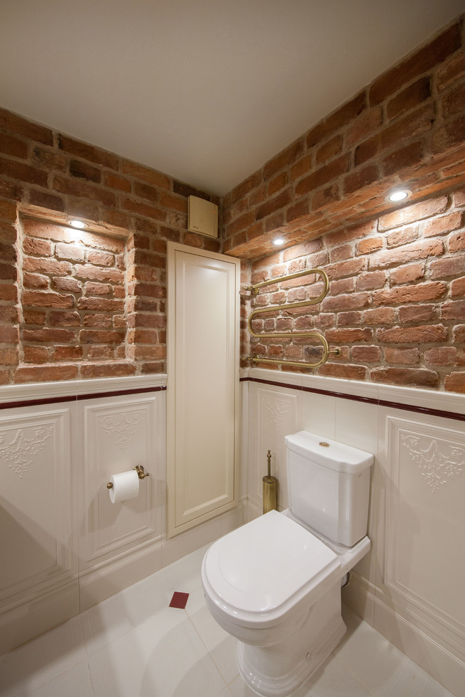 Cette photo montre un WC et toilettes industriel avec WC à poser, un carrelage blanc, un mur rouge, un sol en carrelage de céramique, un lavabo encastré, un plan de toilette en marbre, un sol blanc et un plan de toilette beige.
