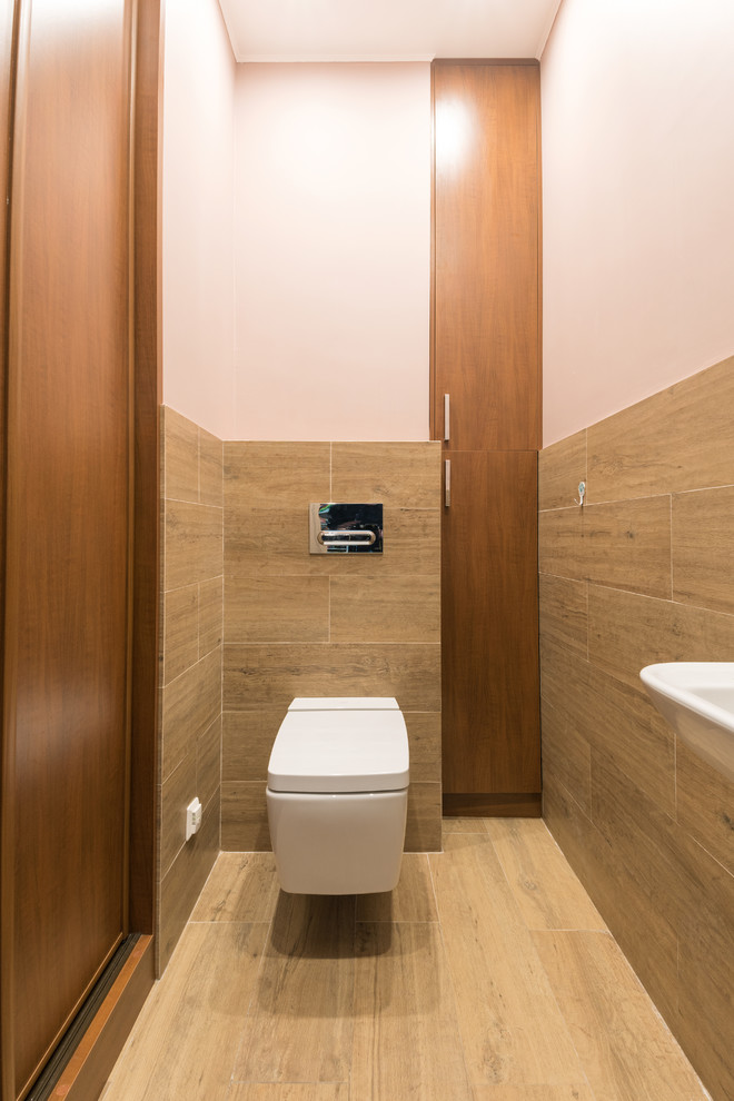 Idée de décoration pour un petit WC suspendu design en bois brun avec un placard à porte plane, un carrelage marron, des carreaux de porcelaine, un mur beige, un sol en carrelage de porcelaine, un lavabo suspendu et un sol marron.