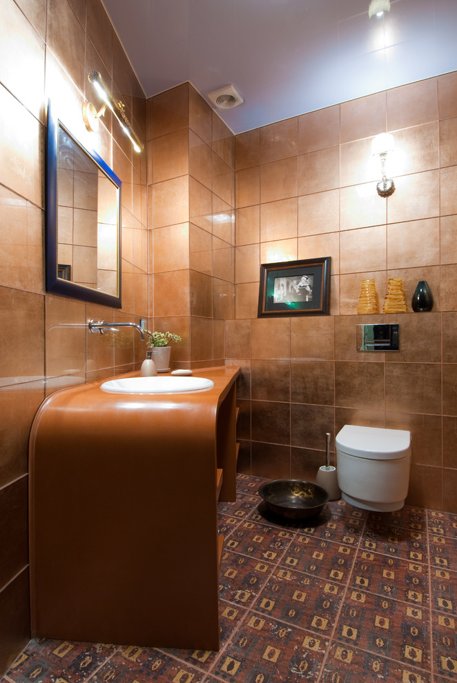 На фото: большой туалет в стиле фьюжн с инсталляцией, коричневой плиткой, стеклянной плиткой, коричневыми стенами, полом из керамической плитки, врезной раковиной и столешницей из искусственного камня
