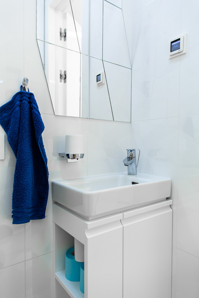 Modelo de aseo contemporáneo con armarios con paneles lisos, puertas de armario blancas, baldosas y/o azulejos blancos y lavabo integrado