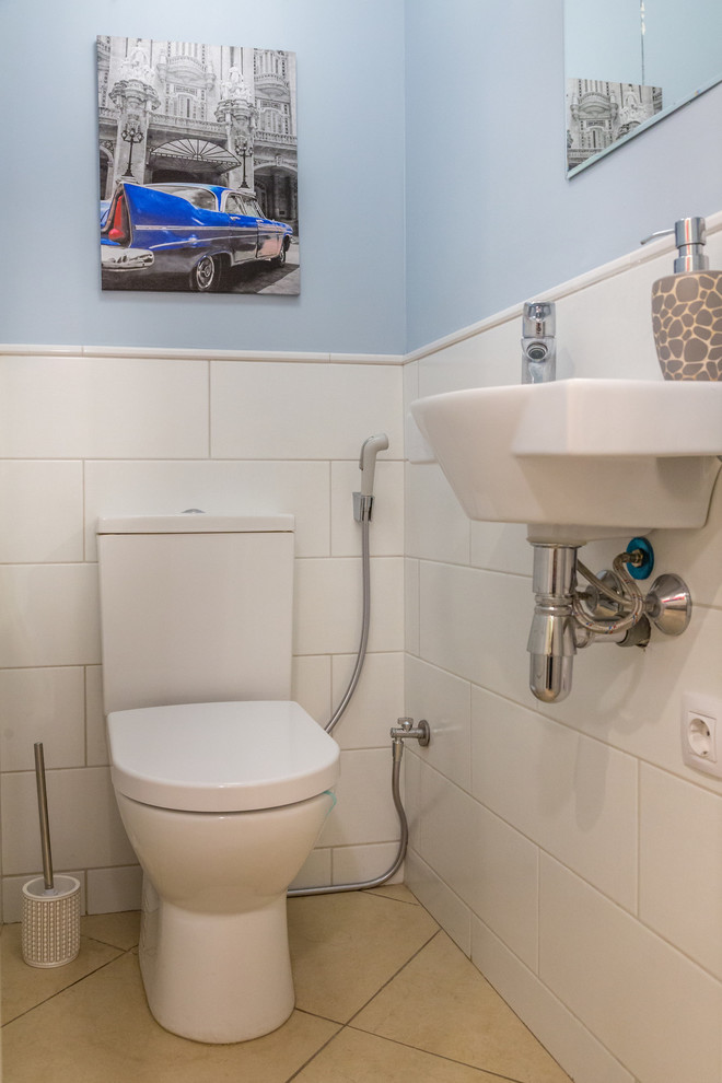 На фото: туалет в скандинавском стиле с раздельным унитазом, белой плиткой, синими стенами и подвесной раковиной с