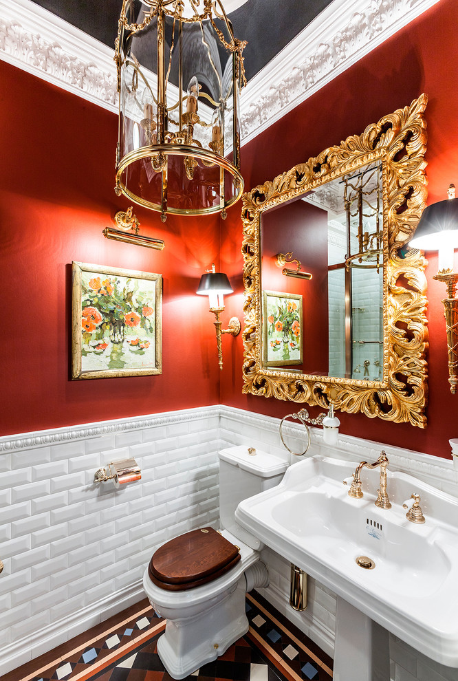 Exempel på ett klassiskt toalett, med en toalettstol med separat cisternkåpa, vit kakel, tunnelbanekakel, röda väggar, ett piedestal handfat och flerfärgat golv