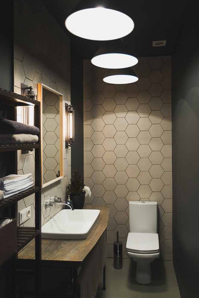 Cette image montre un WC et toilettes urbain avec WC séparés, un carrelage gris, un mur noir, un plan de toilette en bois et un plan de toilette marron.