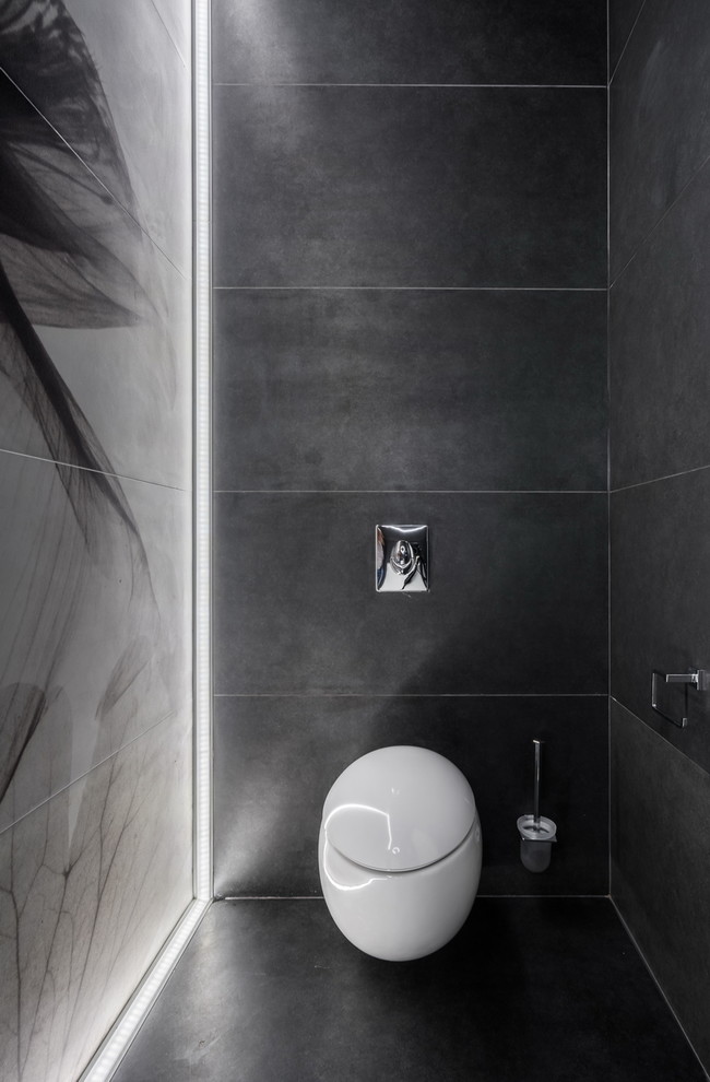 Inspiration pour un WC suspendu design avec un carrelage gris et un sol noir.