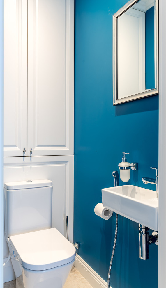 Cette photo montre un WC et toilettes chic avec WC séparés, un mur bleu, un lavabo suspendu et un sol beige.