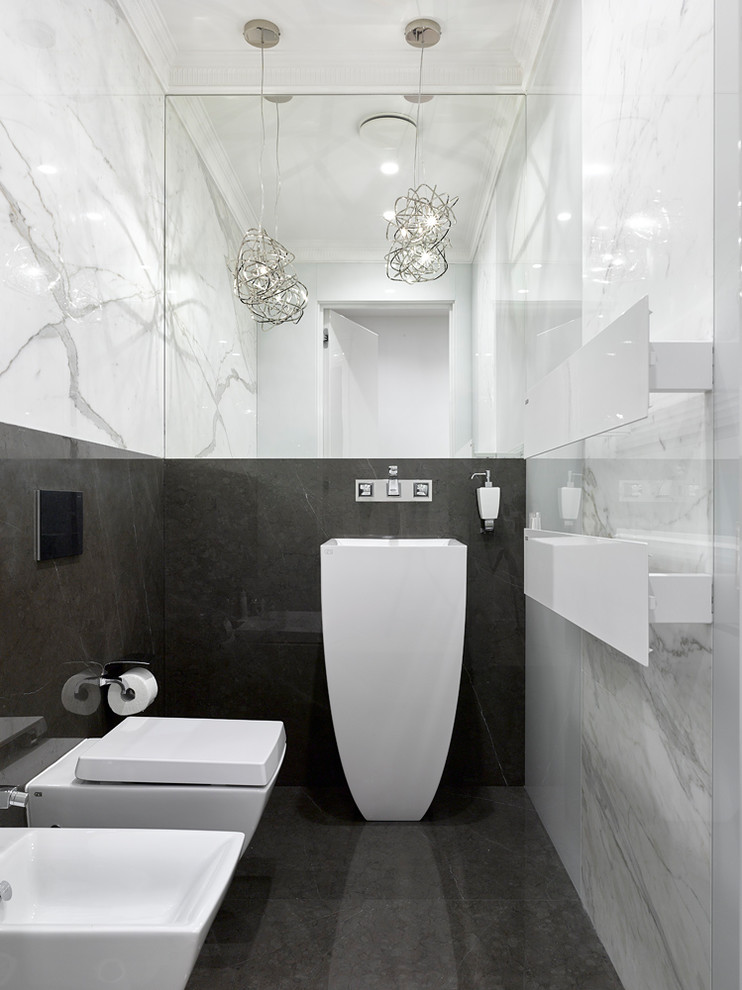 モスクワにあるコンテンポラリースタイルのおしゃれなトイレ・洗面所 (壁掛け式トイレ、ペデスタルシンク、黒い床、照明) の写真