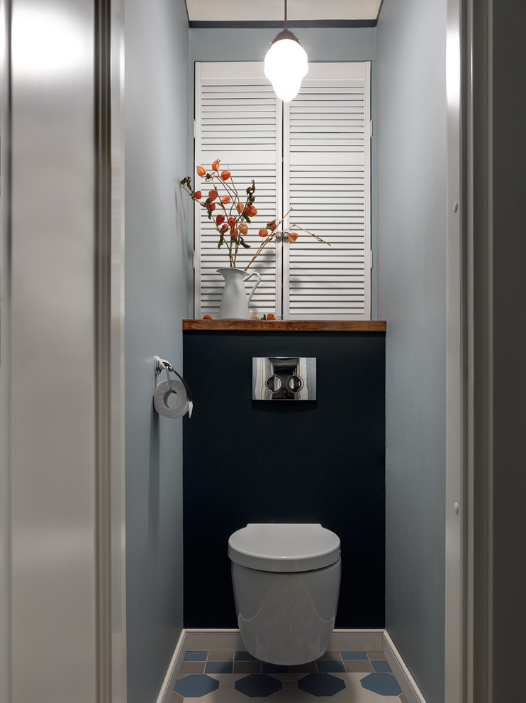 Foto på ett funkis toalett, med en vägghängd toalettstol och flerfärgat golv