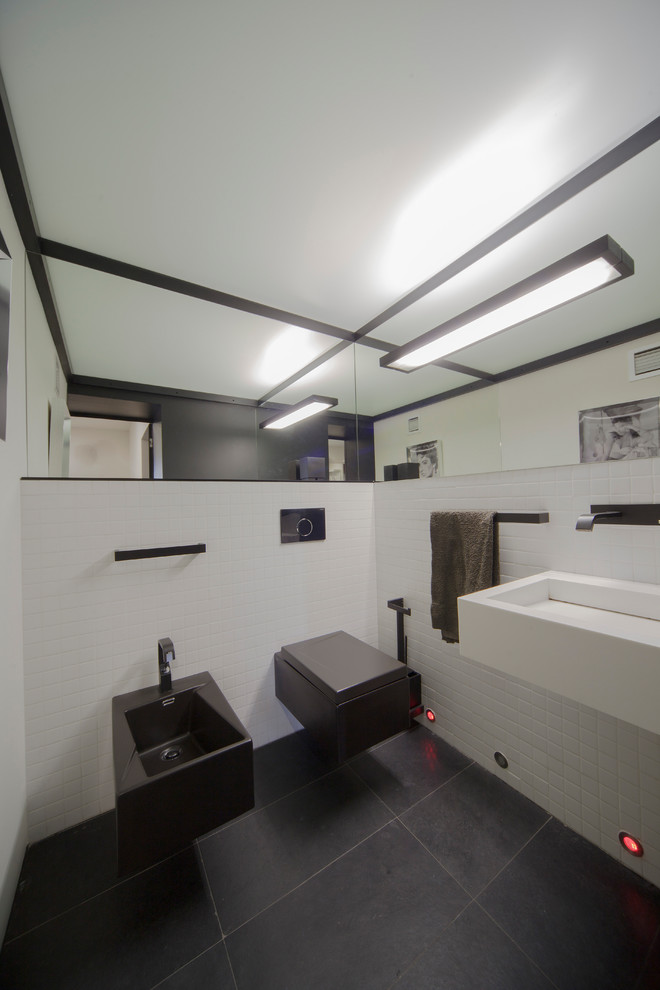 Idee per un piccolo bagno di servizio minimal con WC sospeso, piastrelle bianche, piastrelle in terracotta, pavimento in ardesia, lavabo sospeso e pavimento nero