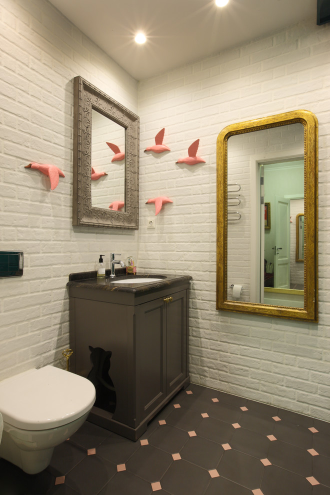 Inredning av ett klassiskt toalett, med bruna skåp, en vägghängd toalettstol, ett undermonterad handfat, luckor med profilerade fronter, vita väggar och flerfärgat golv