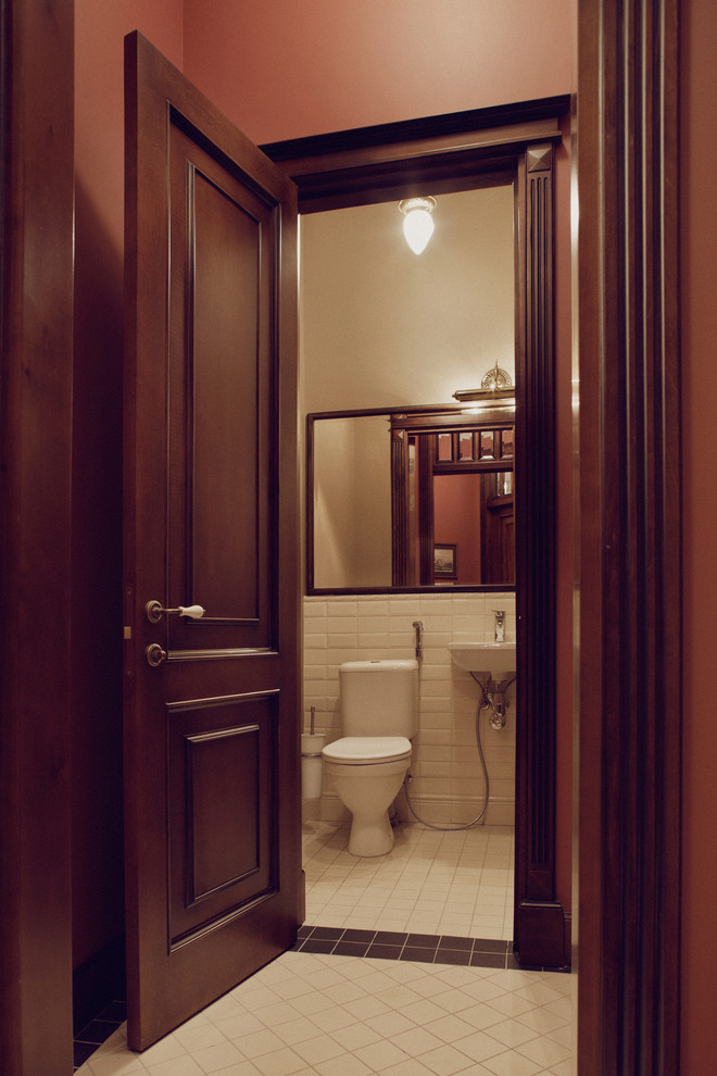 На фото: туалет в классическом стиле с бежевой плиткой, керамической плиткой, бежевыми стенами, полом из керамической плитки и подвесной раковиной