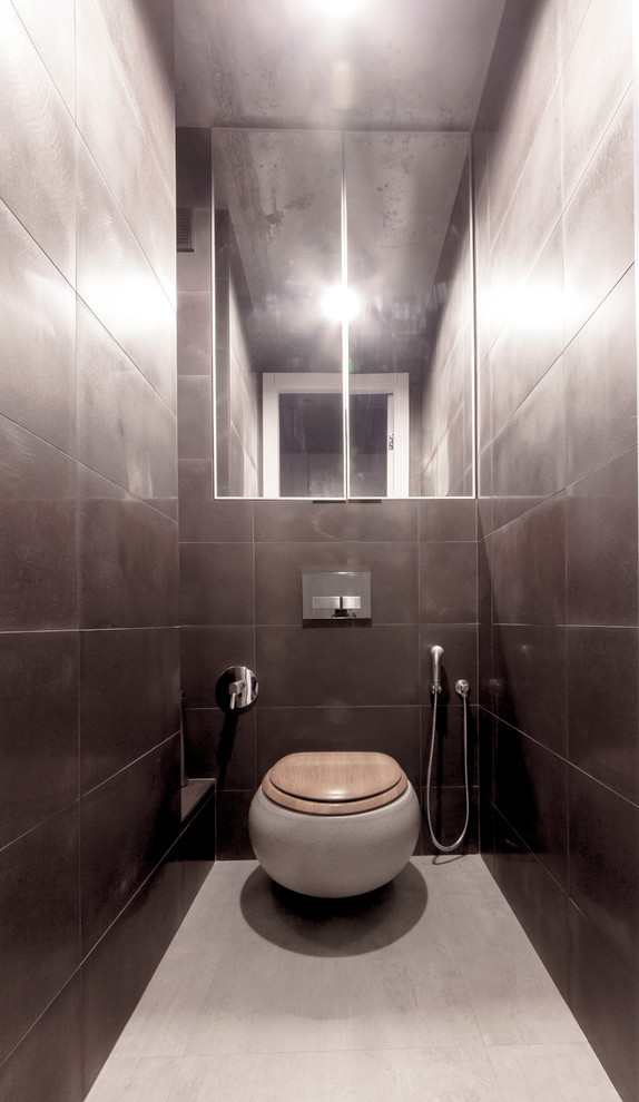 Inredning av ett modernt litet toalett, med en vägghängd toalettstol, svart kakel, kakel i metall och klinkergolv i porslin