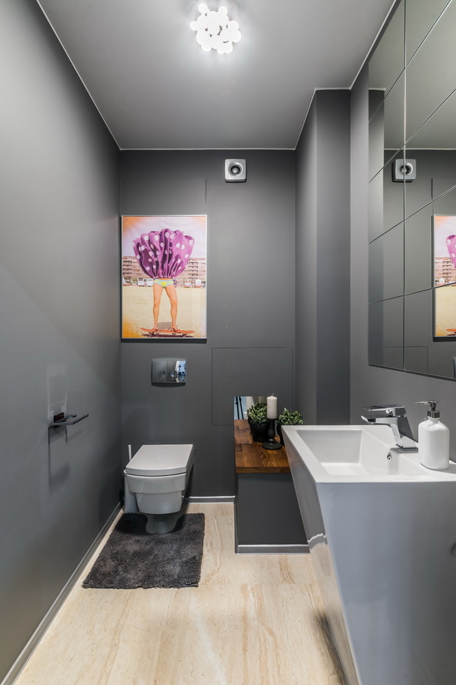 Bild på ett funkis toalett, med en vägghängd toalettstol, grå väggar, ett piedestal handfat och beiget golv