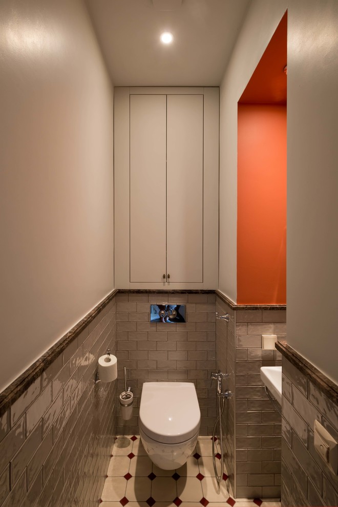 Exemple d'un WC suspendu tendance avec un mur orange, un lavabo suspendu et un sol beige.