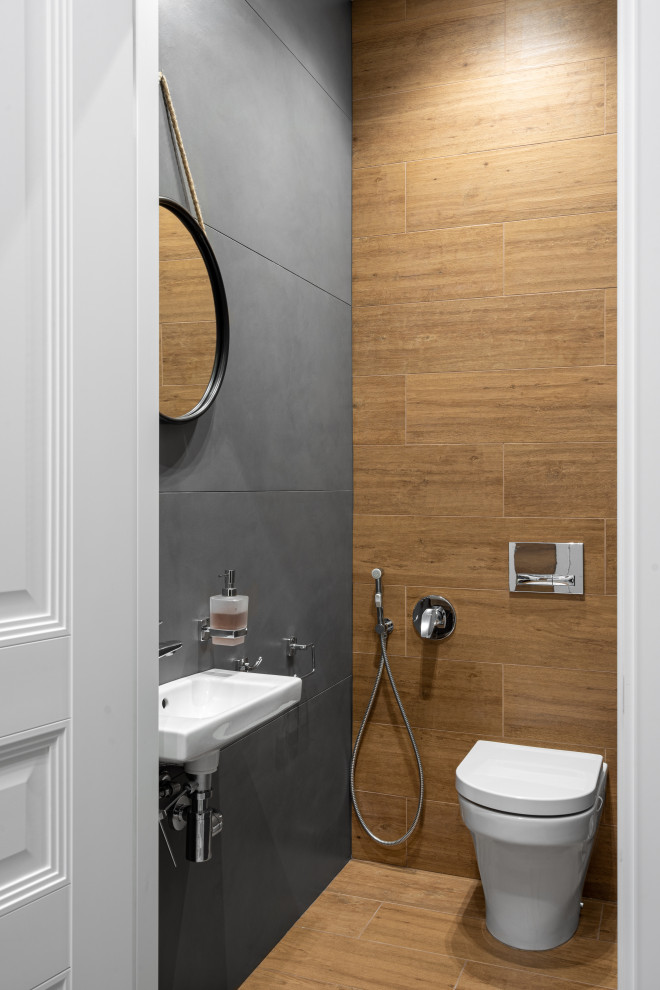 Idée de décoration pour un petit WC et toilettes design avec un carrelage gris et meuble-lavabo suspendu.