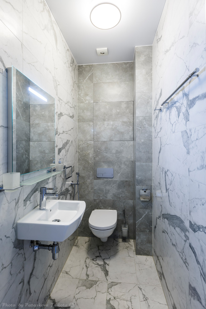 Пример оригинального дизайна: туалет среднего размера в современном стиле с биде, серой плиткой, керамогранитной плиткой, серыми стенами, полом из керамогранита, подвесной раковиной и белым полом