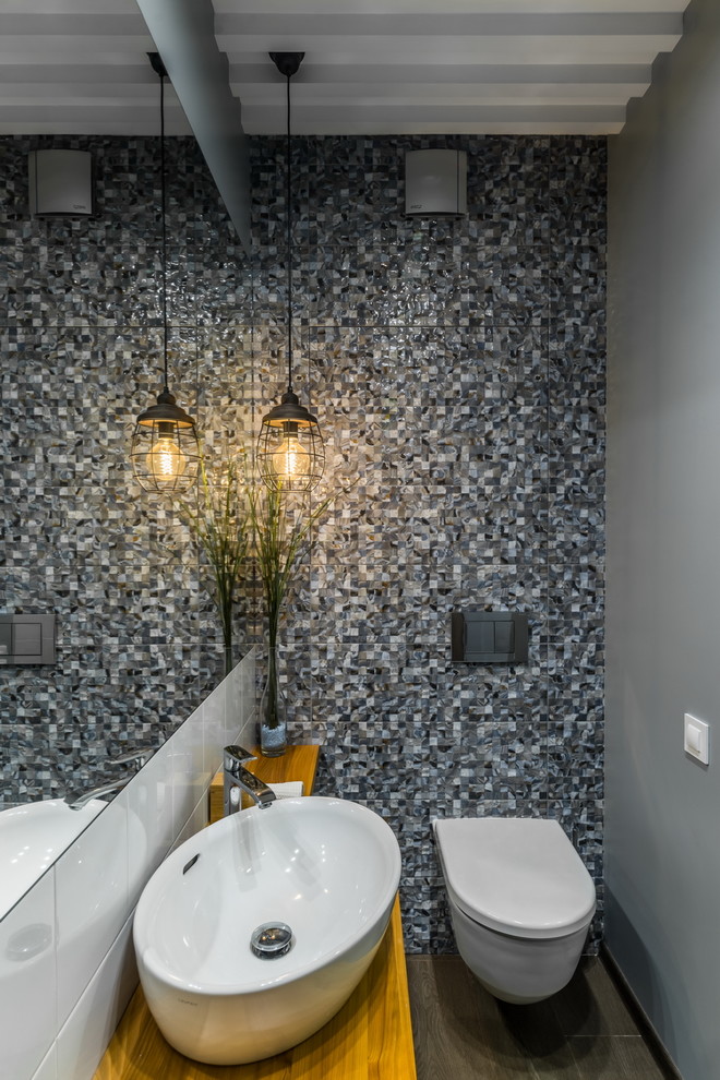 Ispirazione per un bagno di servizio design con WC sospeso, piastrelle grigie, pareti grigie, lavabo a bacinella, top in legno, pavimento marrone e top marrone