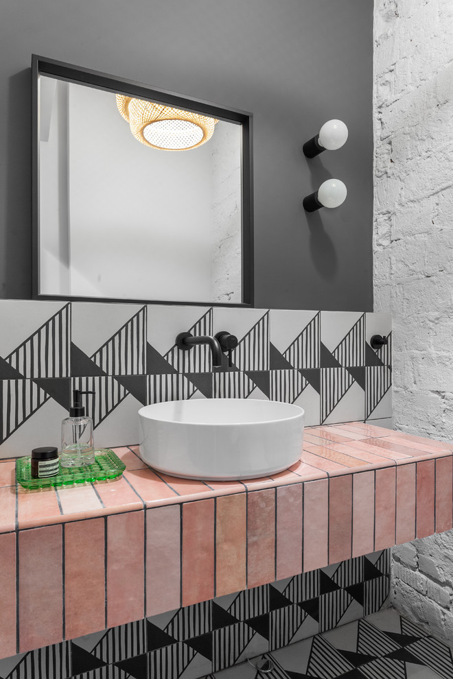 Aménagement d'un WC et toilettes contemporain avec un carrelage noir et blanc, un mur noir, une vasque, un sol multicolore et un plan de toilette marron.