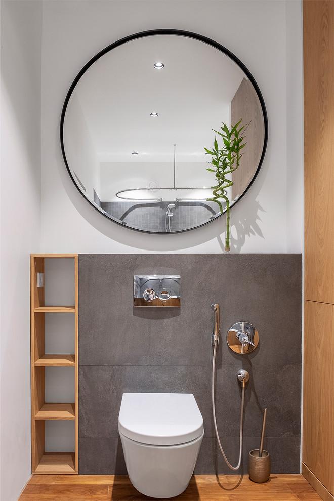 Aménagement d'un WC suspendu contemporain en bois brun de taille moyenne avec un placard à porte plane, un carrelage gris, des carreaux de porcelaine, un mur blanc, un sol en bois brun, une vasque, un sol beige, un plan de toilette en carrelage et un plan de toilette gris.