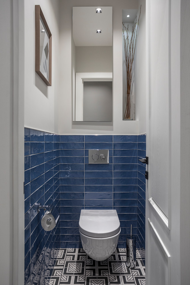 Imagen de aseo actual con sanitario de pared, baldosas y/o azulejos azules, paredes blancas y suelo multicolor