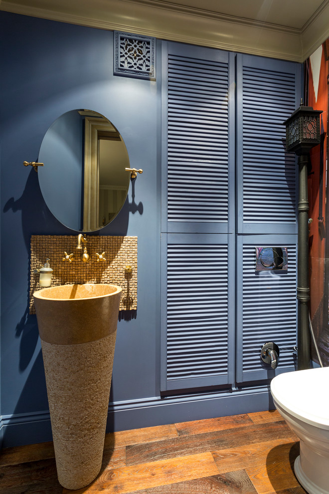 Bild på ett funkis toalett, med en toalettstol med separat cisternkåpa, blå väggar och ett piedestal handfat