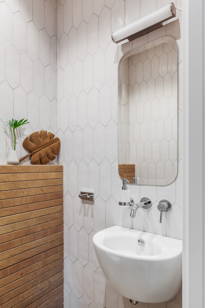 Small scandinavian cloakroom in Moscow with a wall mounted toilet, white tiles, porcelain tiles, white walls, porcelain flooring, a wall-mounted sink and brown floors.