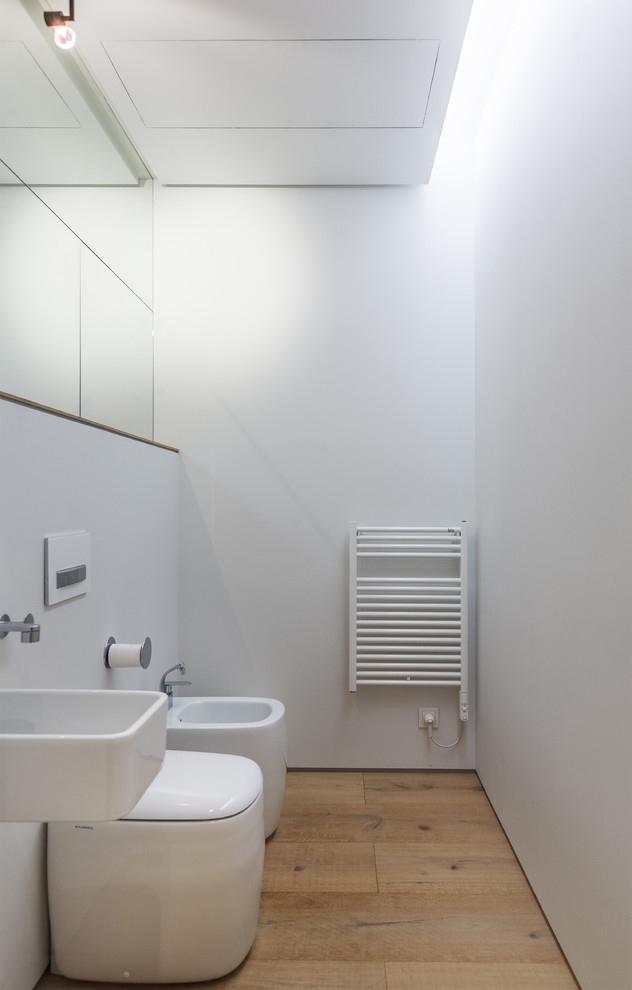 Пример оригинального дизайна: туалет среднего размера в современном стиле с светлым паркетным полом, биде и подвесной раковиной