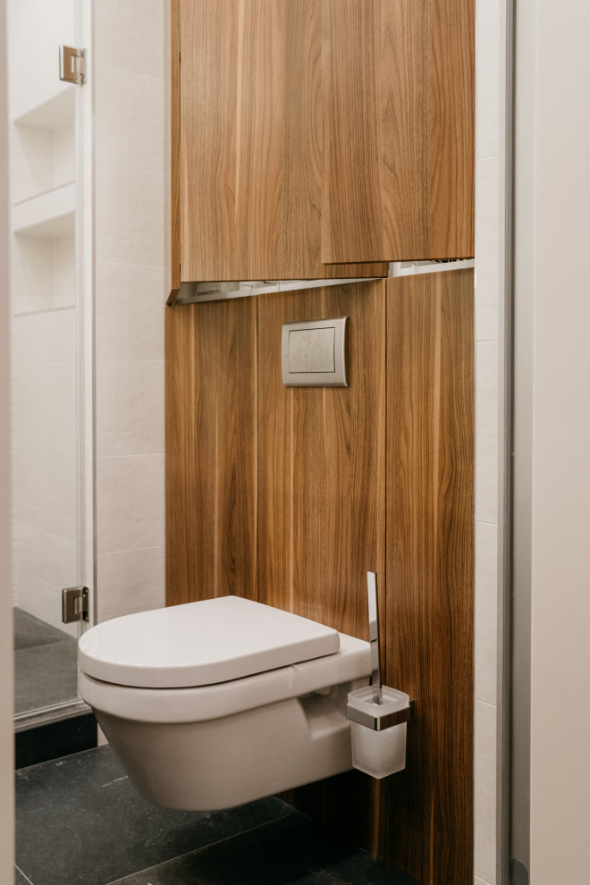 Réalisation d'un petit WC et toilettes design en bois brun avec un placard à porte plane, un carrelage gris, un mur gris, un sol en carrelage de porcelaine, une vasque, un plan de toilette en surface solide, un sol gris, un plan de toilette noir, meuble-lavabo sur pied et boiseries.
