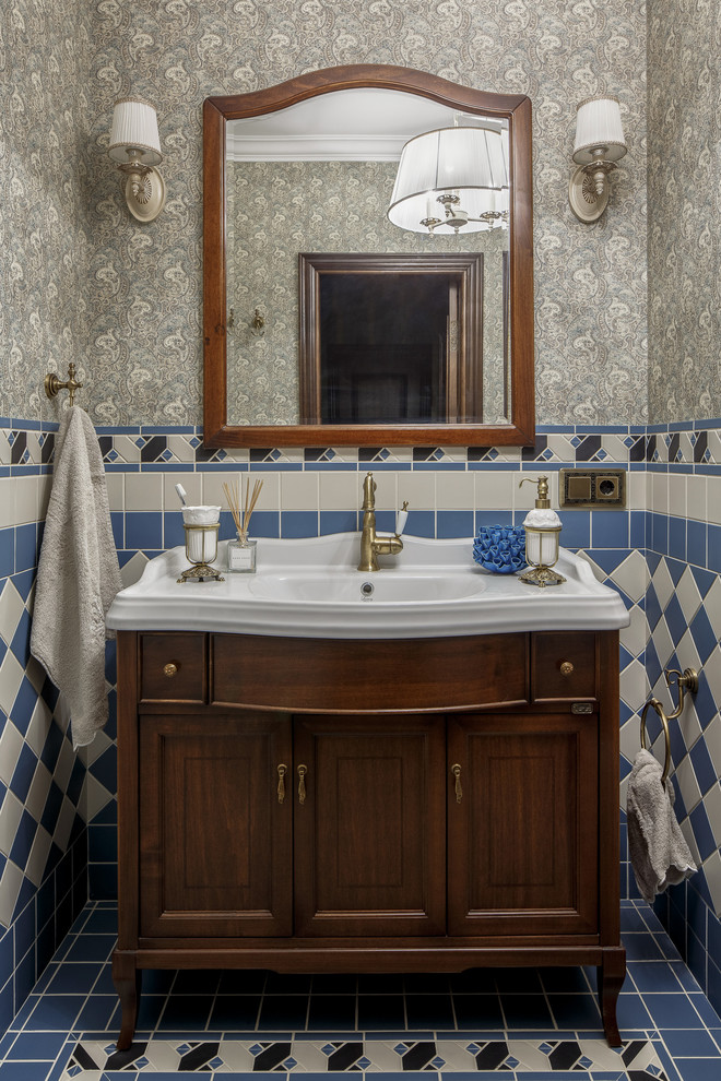 Cette photo montre un petit WC et toilettes en bois foncé avec un placard en trompe-l'oeil, un carrelage beige, un carrelage bleu, un mur gris, un lavabo intégré, un sol bleu et un plan de toilette blanc.