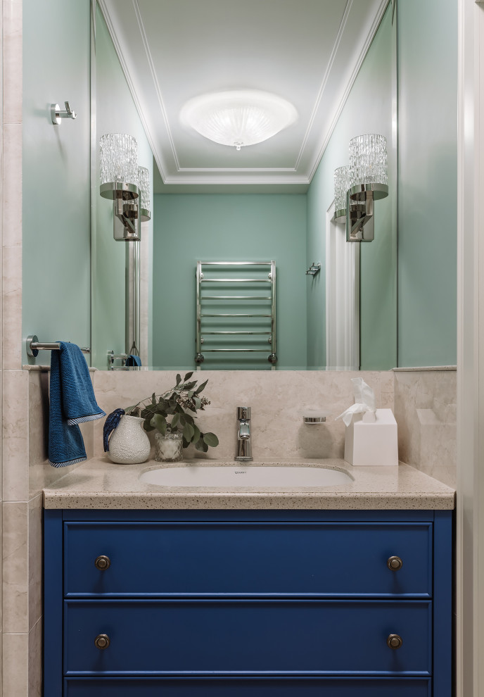 This is an example of a small classic cloakroom in Moscow with beaded cabinets, blue cabinets, a wall mounted toilet, beige tiles, stone slabs, blue walls, ceramic flooring, a submerged sink, solid surface worktops, beige floors, beige worktops and a built in vanity unit.
