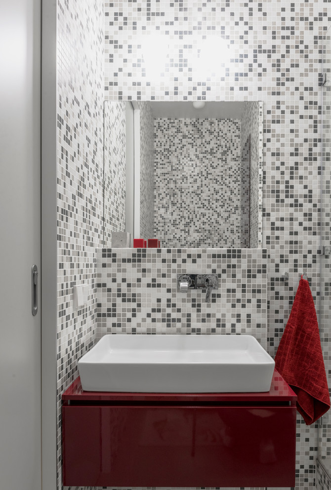 Inspiration for a small contemporary cloakroom in Moscow with flat-panel cabinets, red cabinets, a wall mounted toilet, grey tiles, mosaic tiles, grey walls, cement flooring, a vessel sink, laminate worktops, grey floors and red worktops.