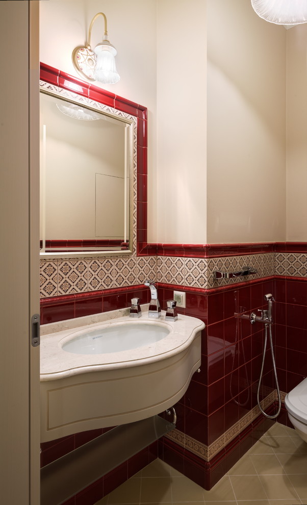 Imagen de aseo clásico con baldosas y/o azulejos rojos, paredes beige y lavabo bajoencimera
