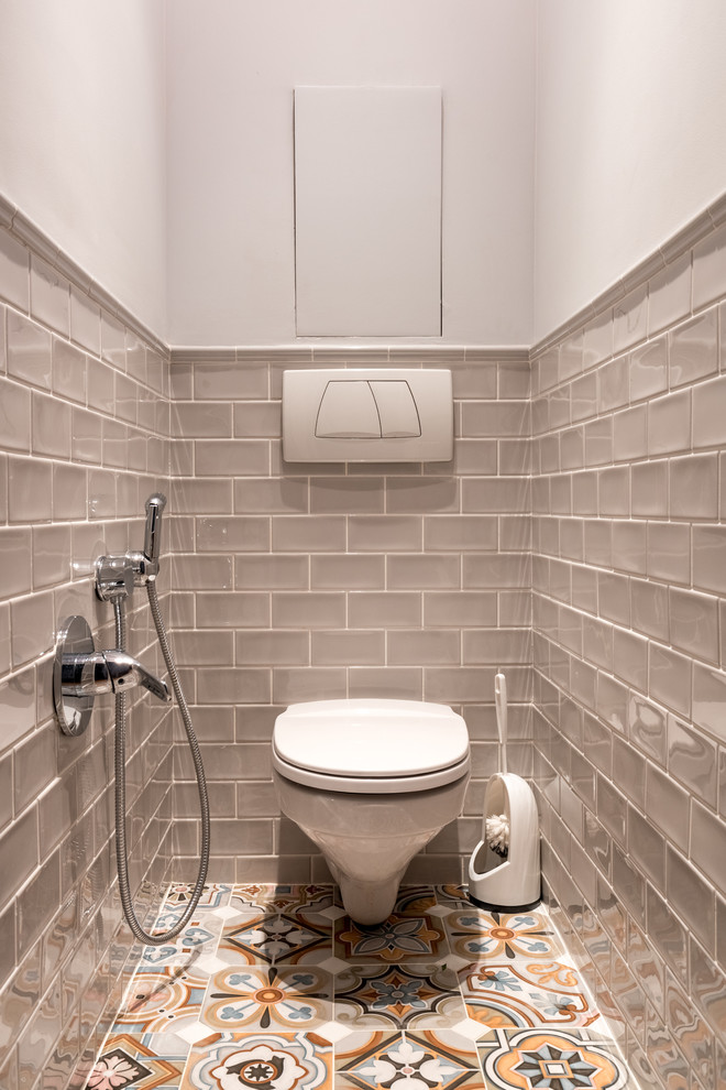 На фото: туалет в стиле неоклассика (современная классика) с инсталляцией, бежевой плиткой, белыми стенами и разноцветным полом