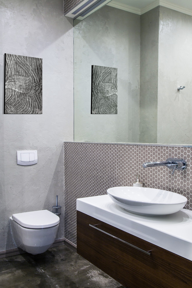 Стильный дизайн: туалет в современном стиле с плоскими фасадами, темными деревянными фасадами, инсталляцией, серой плиткой, плиткой мозаикой, серыми стенами, настольной раковиной, черным полом и белой столешницей - последний тренд