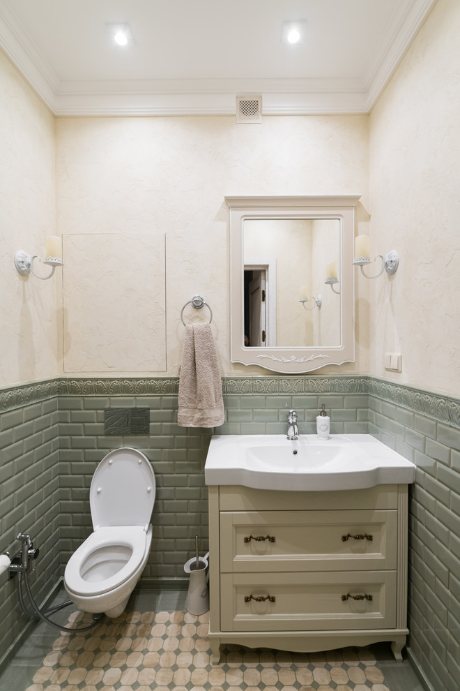 Aménagement d'un WC suspendu classique avec un placard avec porte à panneau encastré, un carrelage vert, un carrelage métro et un mur beige.