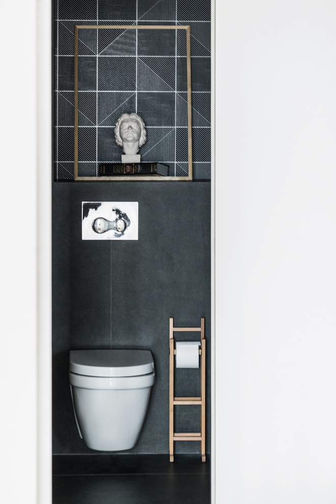 На фото: туалет в современном стиле с инсталляцией, черной плиткой и черным полом с