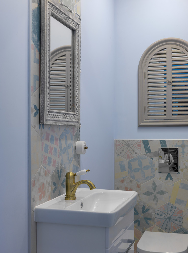 Klassische Gästetoilette mit flächenbündigen Schrankfronten, weißen Schränken, farbigen Fliesen, Wandtoilette, integriertem Waschbecken und blauer Wandfarbe in Moskau