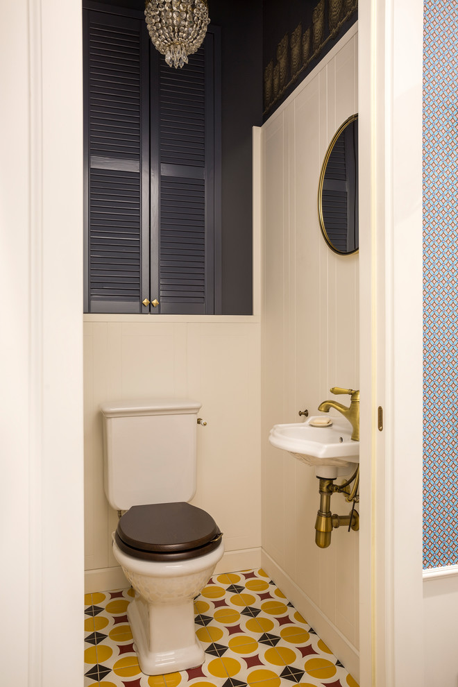 Idee per un bagno di servizio design con WC a due pezzi, pareti blu, lavabo sospeso e pavimento multicolore