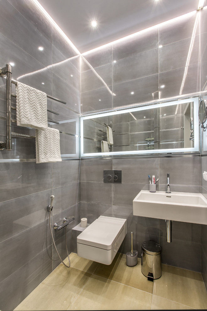 Idéer för ett modernt toalett, med en vägghängd toalettstol, grå kakel, ett väggmonterat handfat och beiget golv