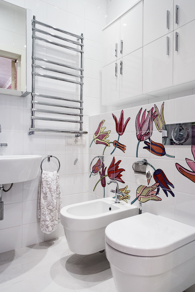サンクトペテルブルクにあるコンテンポラリースタイルのおしゃれなトイレ・洗面所 (壁付け型シンク、フラットパネル扉のキャビネット、白いキャビネット、白いタイル、ビデ、白い壁) の写真