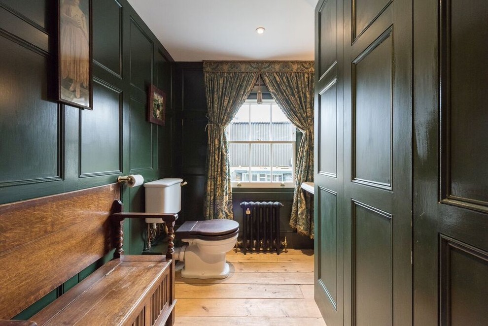 Photo of a medium sized victorian cloakroom in London with a two-piece toilet, green walls, light hardwood flooring and beige floors.