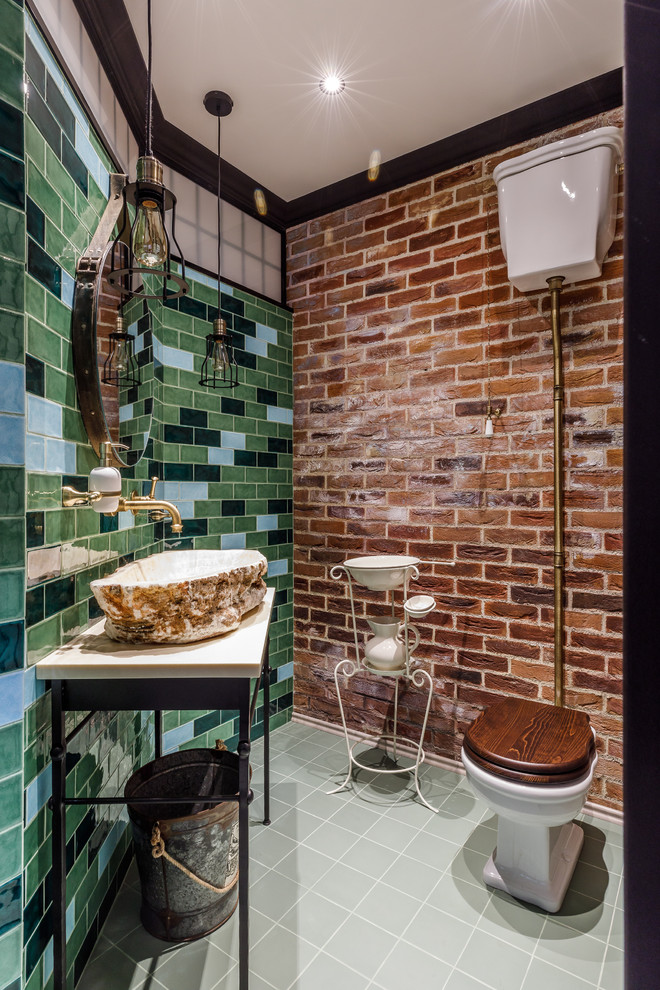 Идея дизайна: туалет: освещение в стиле фьюжн с унитазом-моноблоком, синей плиткой, зеленой плиткой, настольной раковиной, серым полом и бежевой столешницей