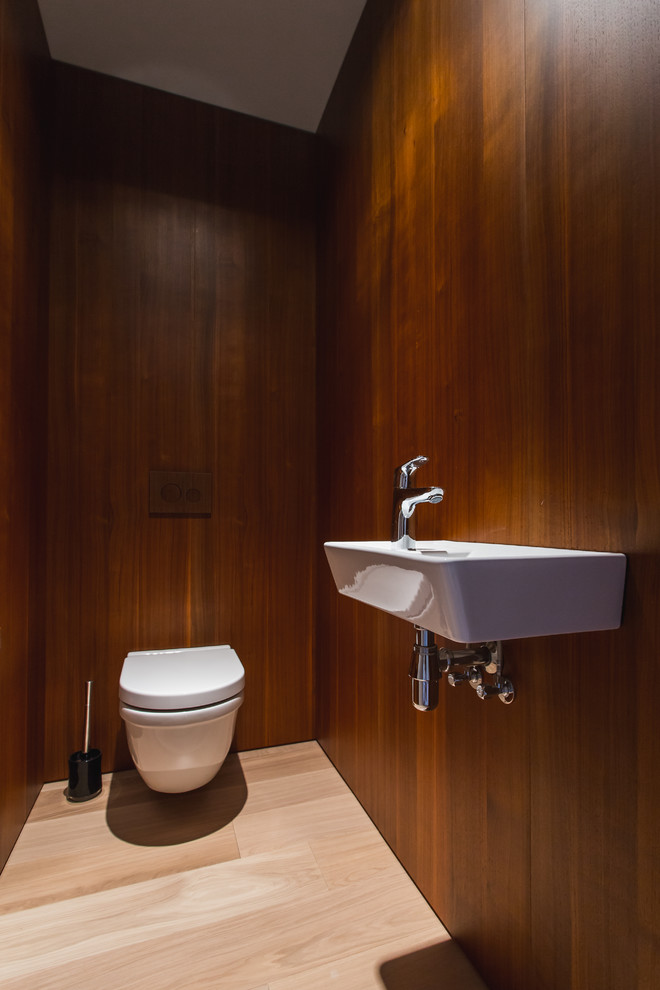 Photo of a contemporary cloakroom in Moscow with a wall mounted toilet, brown walls, a wall-mounted sink and beige floors.